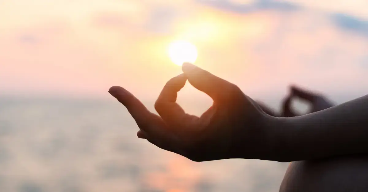 Meditation Mantras: Unlocking Peace and Focus in Life 2024 1 Meditation Mantras: a person is mediating. On the background is a sunset