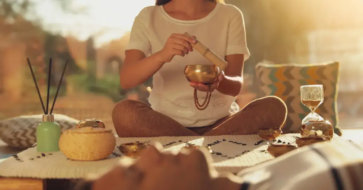 Meditation for Emotional Healing: Guide to Inner Peace 2024 1 Meditation for Emotional Healing: a person lie and meditate. In the back a woman is sitting with a singing bowl