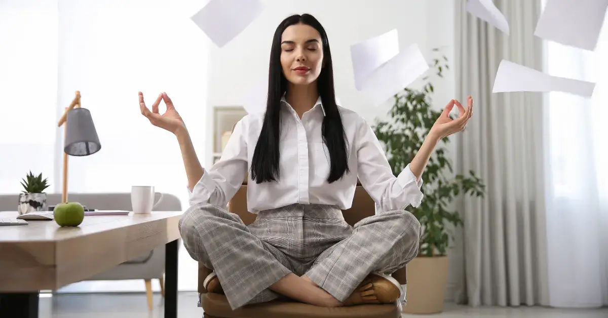 Meditation For Stress Relief At Work: For A Calmer Day 2024 1 Meditation for Stress Relief at Work: a woman is sitting in the office and meditate on her chair.